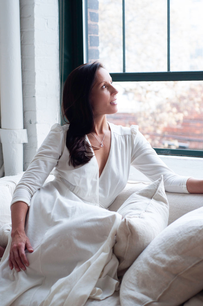 Rachel Ackley in organic cotton ankle long healer dress in white sitting by window
