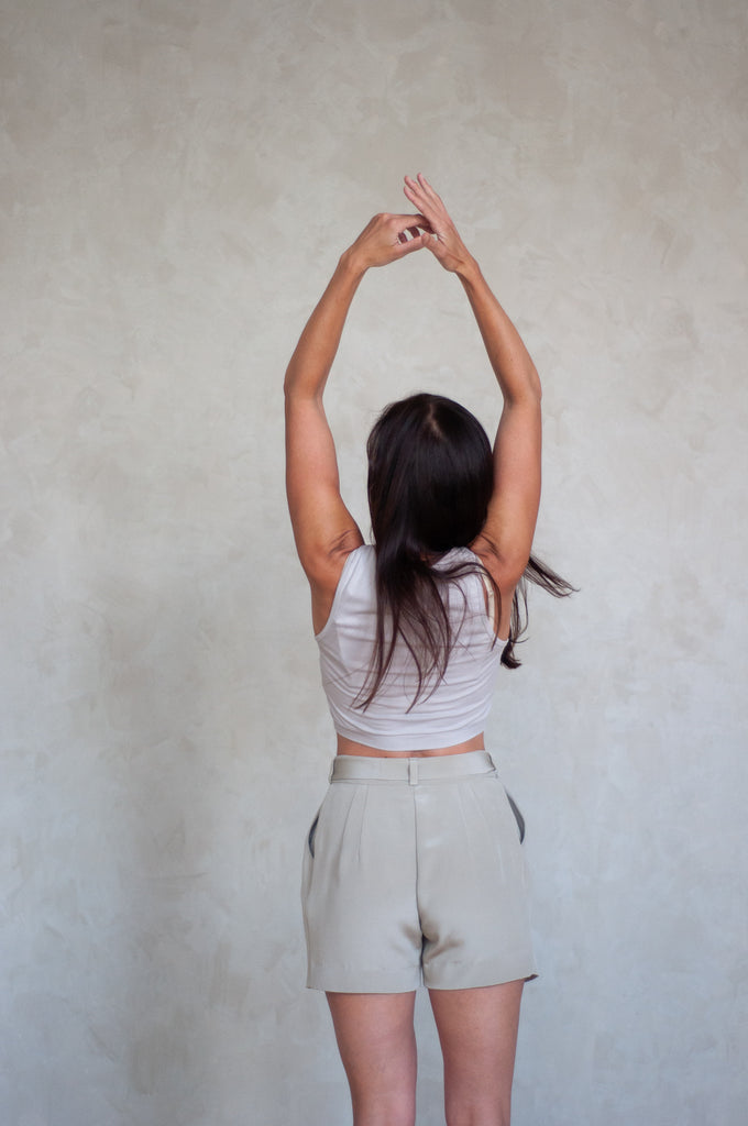 Rachel Ackley in grey organic cotton crop tank and 4 ply silk crepe paper bag tie shorts in color ivory back view