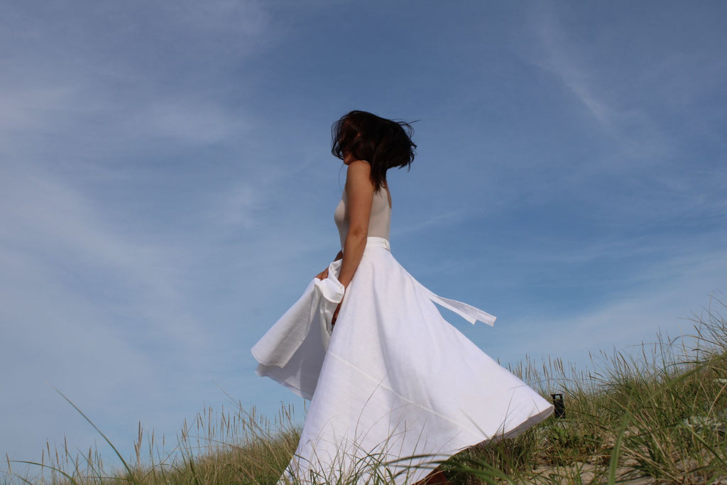 Rachel Ackley in linen healer skirt in white on the beach side back view