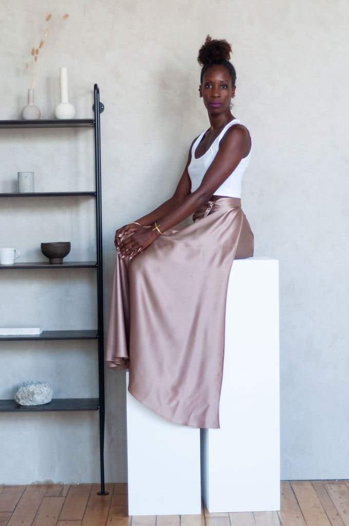 Ssanyu in white organic cotton crop tank and blush Healer skirt in silk charmeuse sitting side view